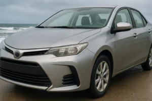 Carro prata estacionado próximo ao mar com gotas de água sobre a lataria, destacando os efeitos da maresia e a importância da proteção contra corrosão.